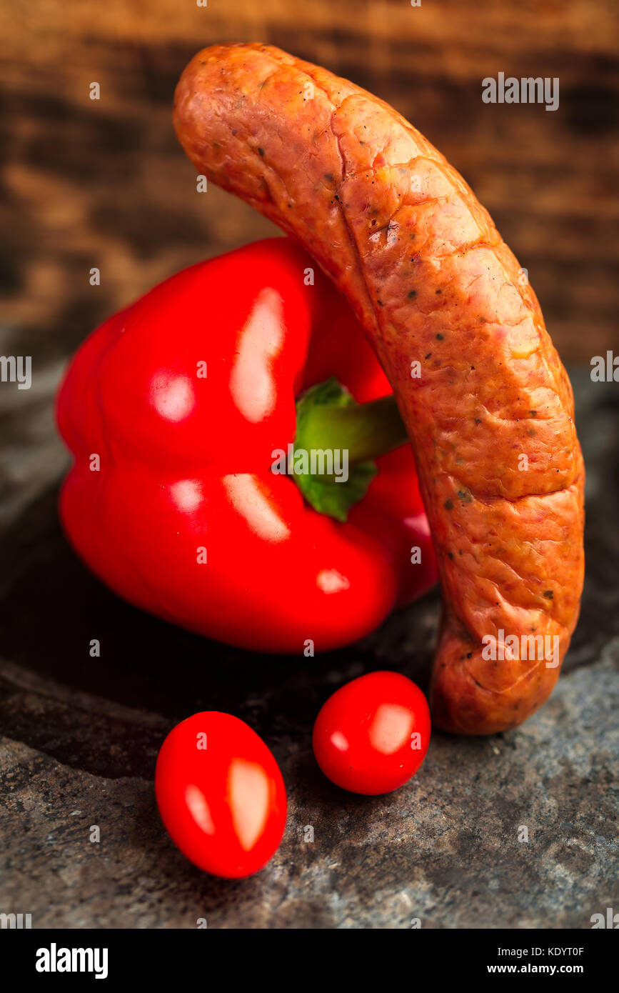 Deliziosamente affumicati artigianali isterband svedese salsicce con budello naturale insieme con il peperone rosso e i pomodori. Foto Stock