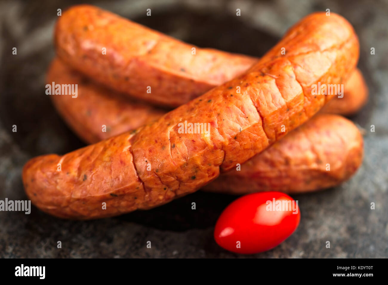 Pila di deliziosamente affumicati artigianali isterband svedese salsicce con budello naturale. qui con un pomodoro. Foto Stock