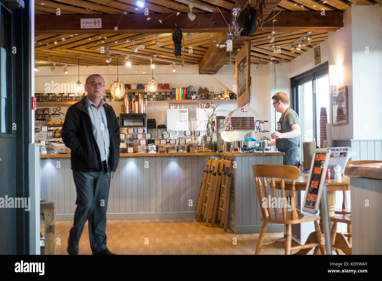 Il cliente arriva al premiato cafe la montagna cafe come un barista fa caffè dietro il bancone, Aviemore Scozia, Regno Unito Foto Stock