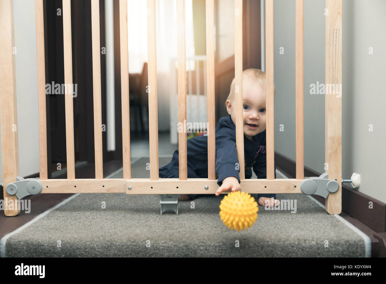 Bambino gettando palla lontano attraverso i cancelli di sicurezza anteriore di scale Foto Stock