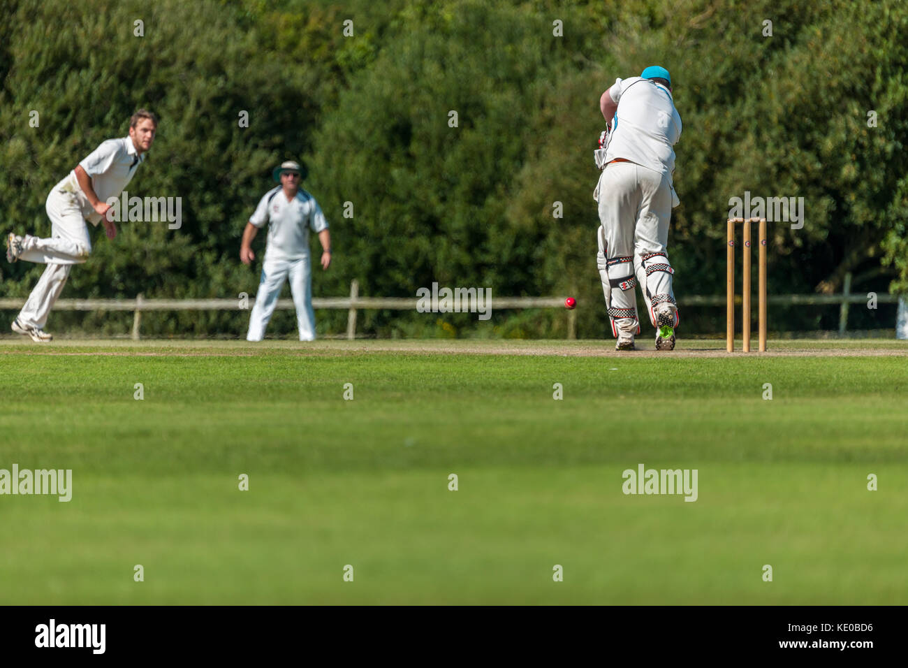 Un battitore gioca un colpo durante una domenica League match tra due locali squadre di cricket. Foto Stock