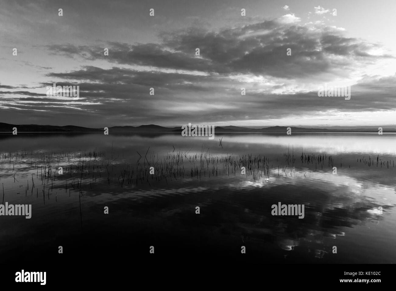 Perfetta e simmetrica nuvole riflessioni su un lago al tramonto Foto Stock