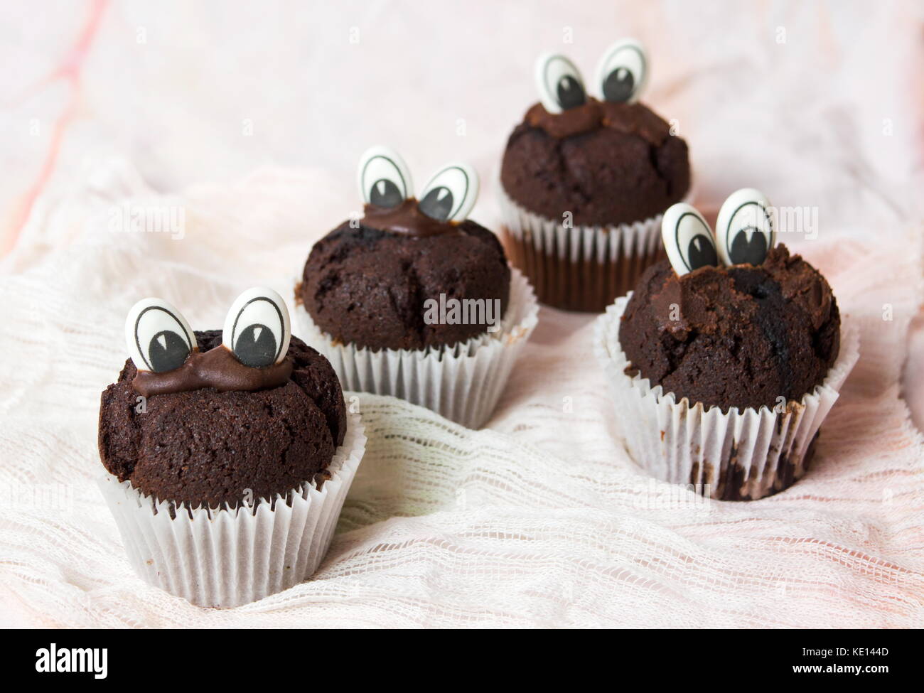 Muffin al cioccolato con occhi commestibili in titolari della carta Foto Stock