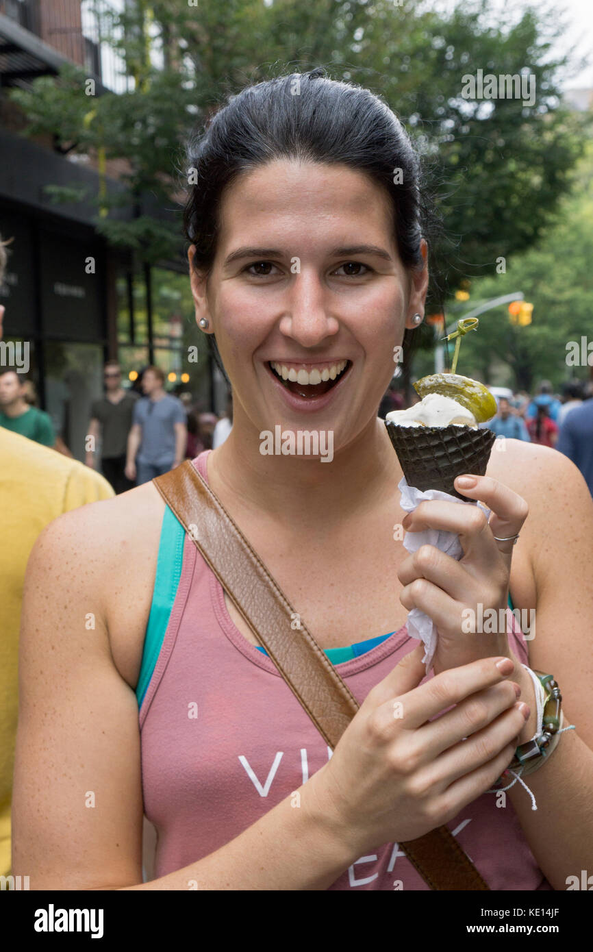 Una donna con un cono gelato guarnito con un aspro pickle all annuale Pickle Day celebrazione su Orchard Street sulla Lower East Side di Manhattan Foto Stock