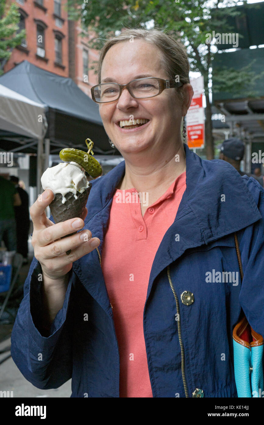Una donna con un cono gelato guarnito con un aspro pickle all annuale Pickle Day celebrazione su Orchard Street sulla Lower East Side di Manhattan Foto Stock