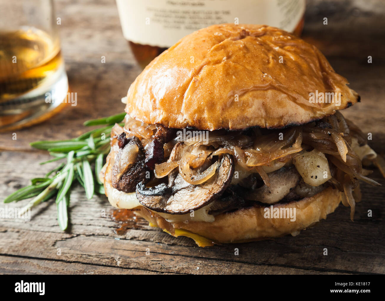 Burger con funghi, cipolle fritte e formaggio su sfondo rustico Foto Stock