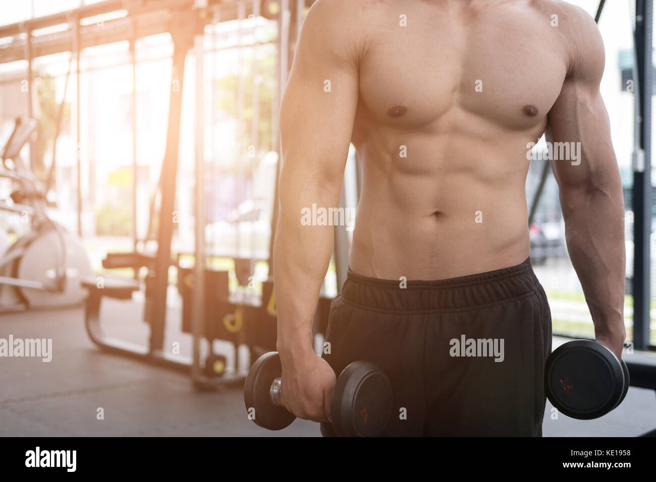 Giovane uomo sollevare pesi nella palestra. bodybuilder maschio fuori lavoro nel centro fitness. sport ragazzo facendo esercizi nel club salute. Foto Stock