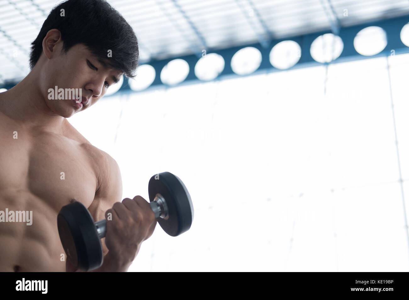 Giovane uomo sollevare pesi nella palestra. bodybuilder maschio fuori lavoro nel centro fitness. sport ragazzo facendo esercizi nel club salute. Foto Stock