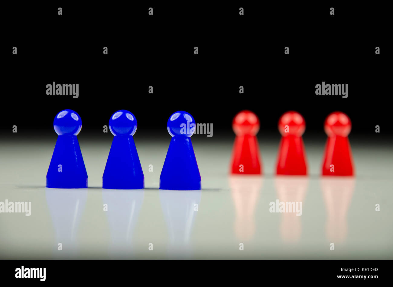 Vista ravvicinata di due righe di figure colorate con sfocato nero e sfondo bianco con la riflessione Foto Stock