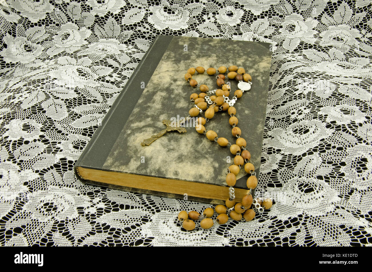 Ancora vita con chiuso vecchio libro in cuoio rilegatura e. perle antiche giacenti su una tovaglia di pizzo Foto Stock