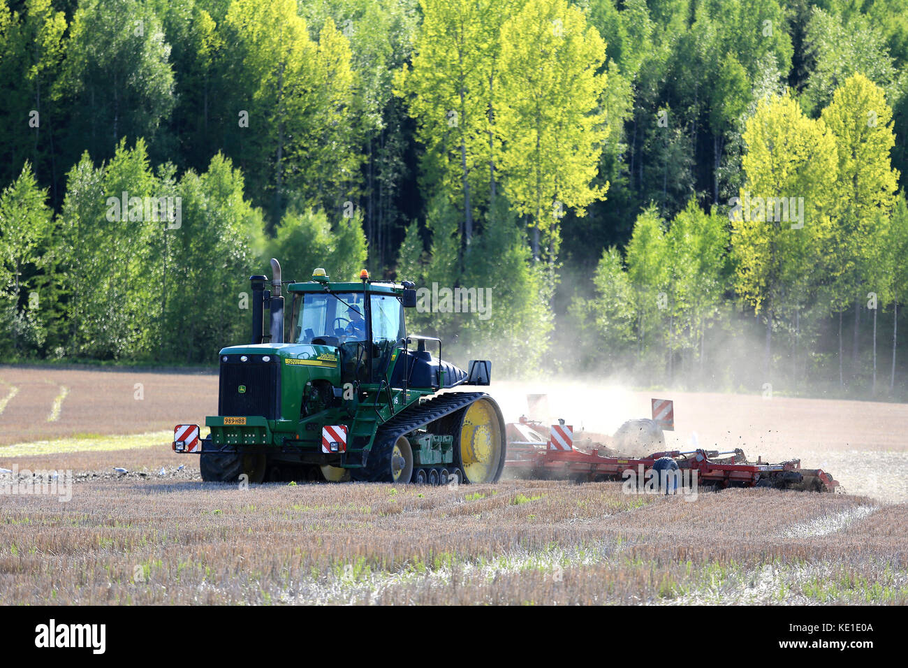 Salo, Finlandia - 27 maggio 2016: John Deere 9520t trattore agricolo cingolato e coltivatore sul campo in primavera nel sud della Finlandia. Foto Stock