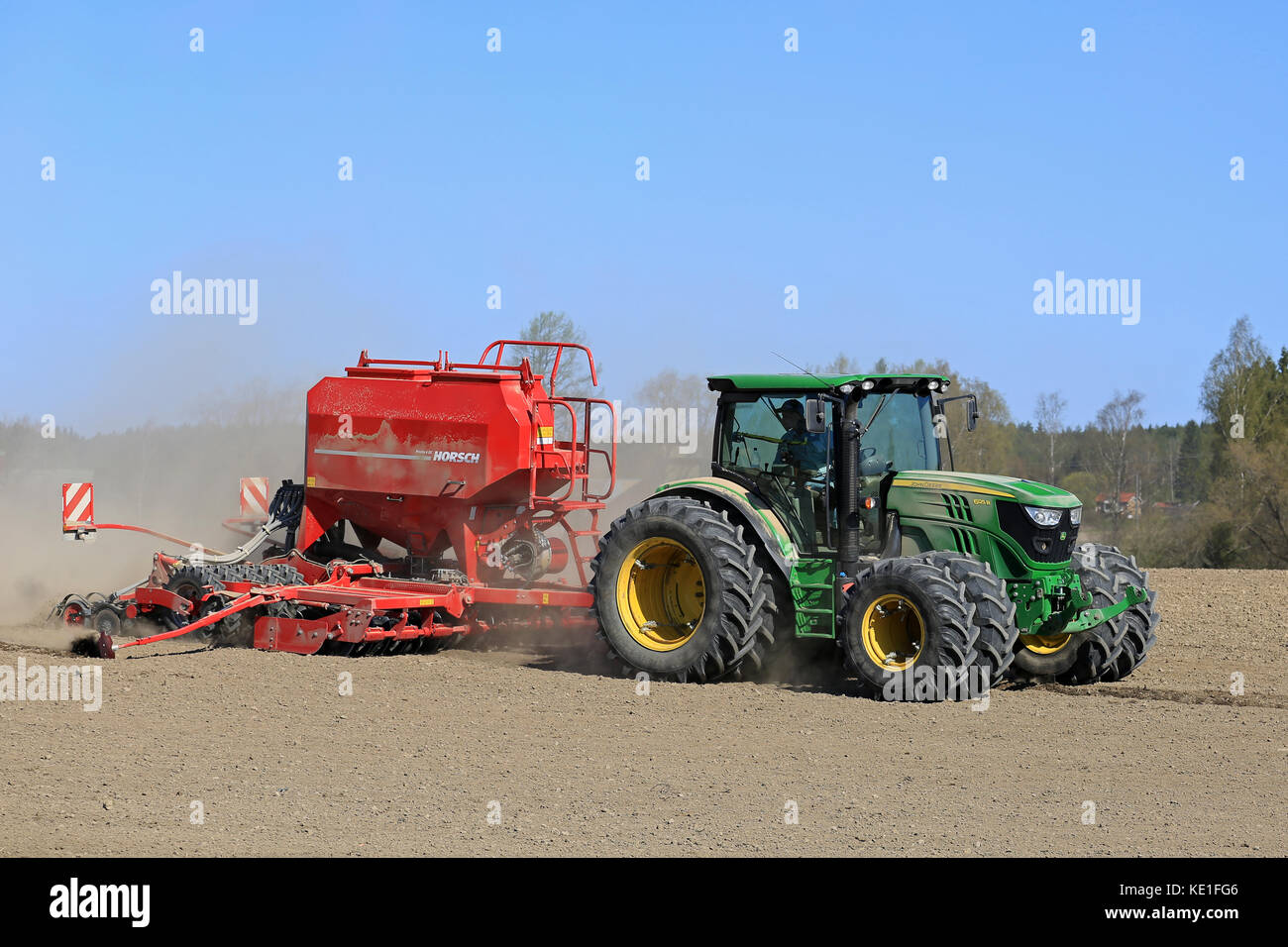 Salo, Finlandia - 8 maggio 2016: John Deere 6125r trattore agricolo e horsch seminatrice sul campo polveroso a molla con cielo blu. Foto Stock