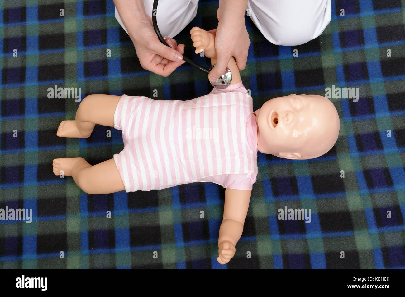 Infant prima serie di aiuto - primo soccorso istruttore che mostra come impulso di controllo sul manichino neonato utilizzando uno stetoscopio Foto Stock