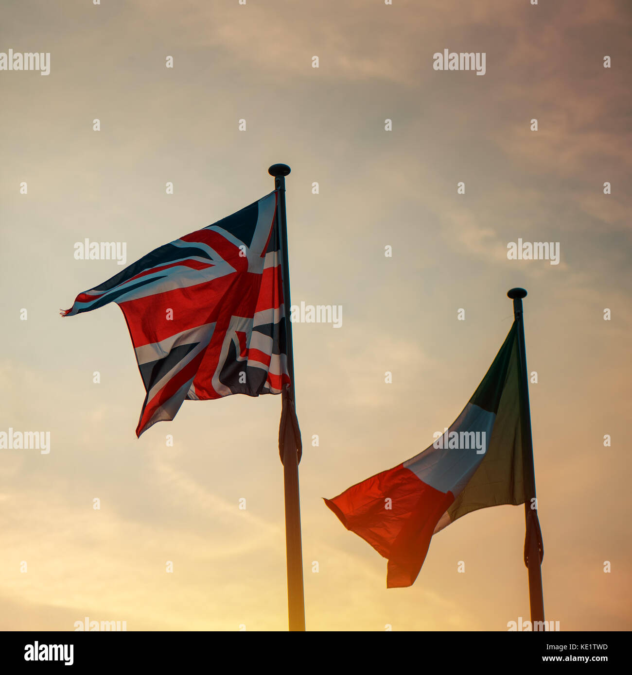 Italiano e bandiera britannica su un palo in sunset, due bandiere nazionali di Italia e Regno Unito (Gran Bretagna) sventolare nel vento. Foto Stock