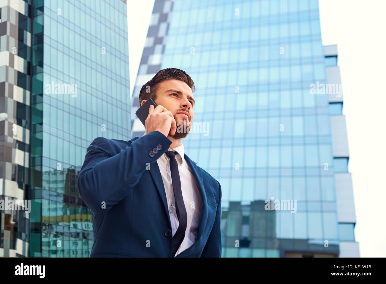 Imprenditore con una barba parlando al telefono contro un edificio Foto Stock