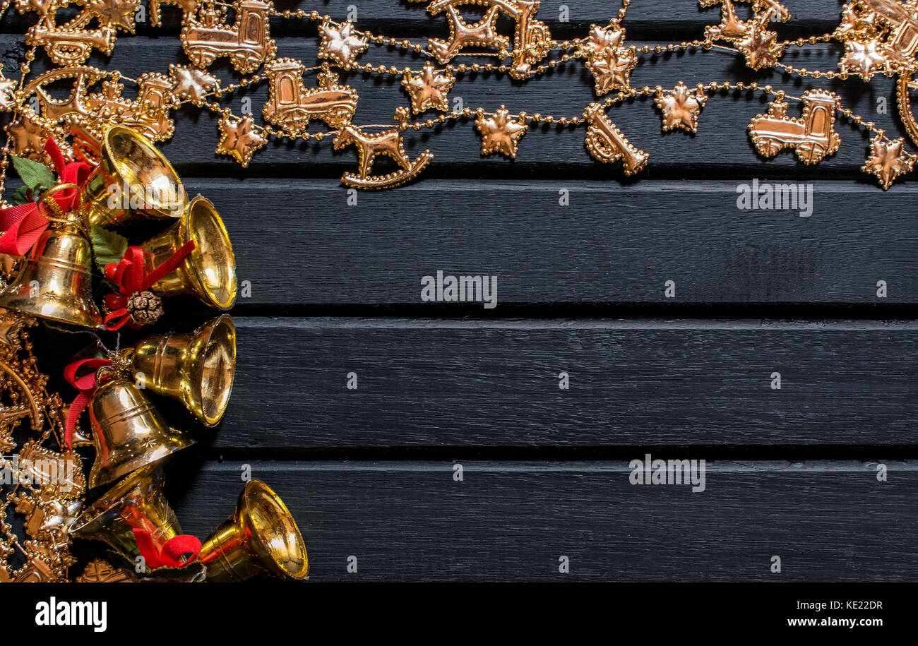 Decorazione di Natale sfondo nero a sfondo di legno, con campane, vischio, golden catene, sfere e puntelli e la catena con le renne e arredamento Foto Stock