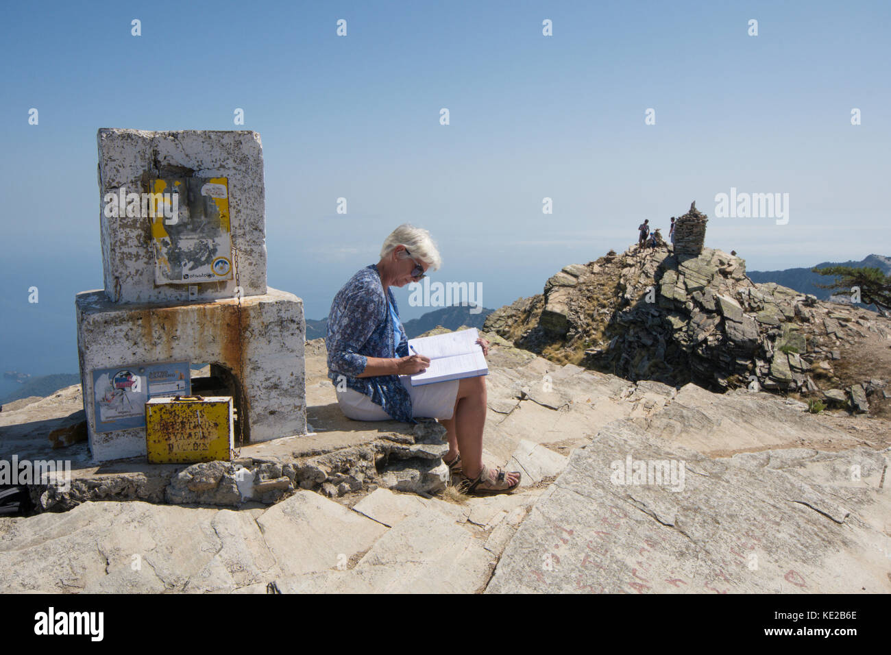 La donna a firmare il libro a sinistra in pietra bianca di sicuro per registrare i visitatori alla sommità del Ipsarion moutain, Thassos, Grecia, isola greca, Settembre. Foto Stock