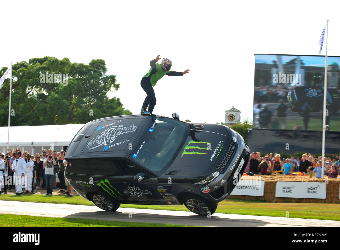 Un stunt driver sorge sulla sommità di una vettura in movimento al 2017 Goodwood Festival della velocità. Foto Stock