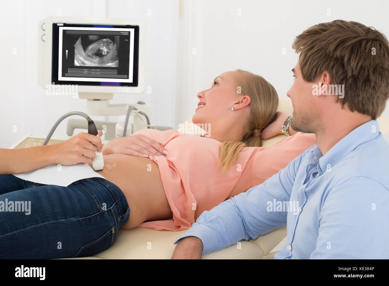 Il marito guardando al medico di eseguire la scansione a ultrasuoni aspettavo Giovane Donna Foto Stock