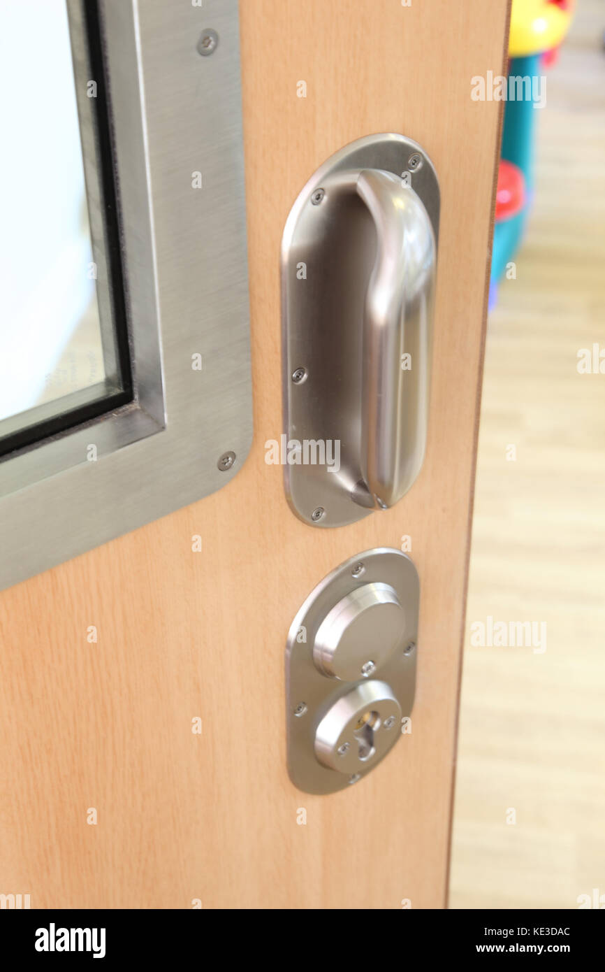 Primo piano di una porta in un'unità psichiatrica sicura del Regno Unito. Mostra maniglia e serratura della porta antilegatura e pannello vetrato ad alta sicurezza. Foto Stock