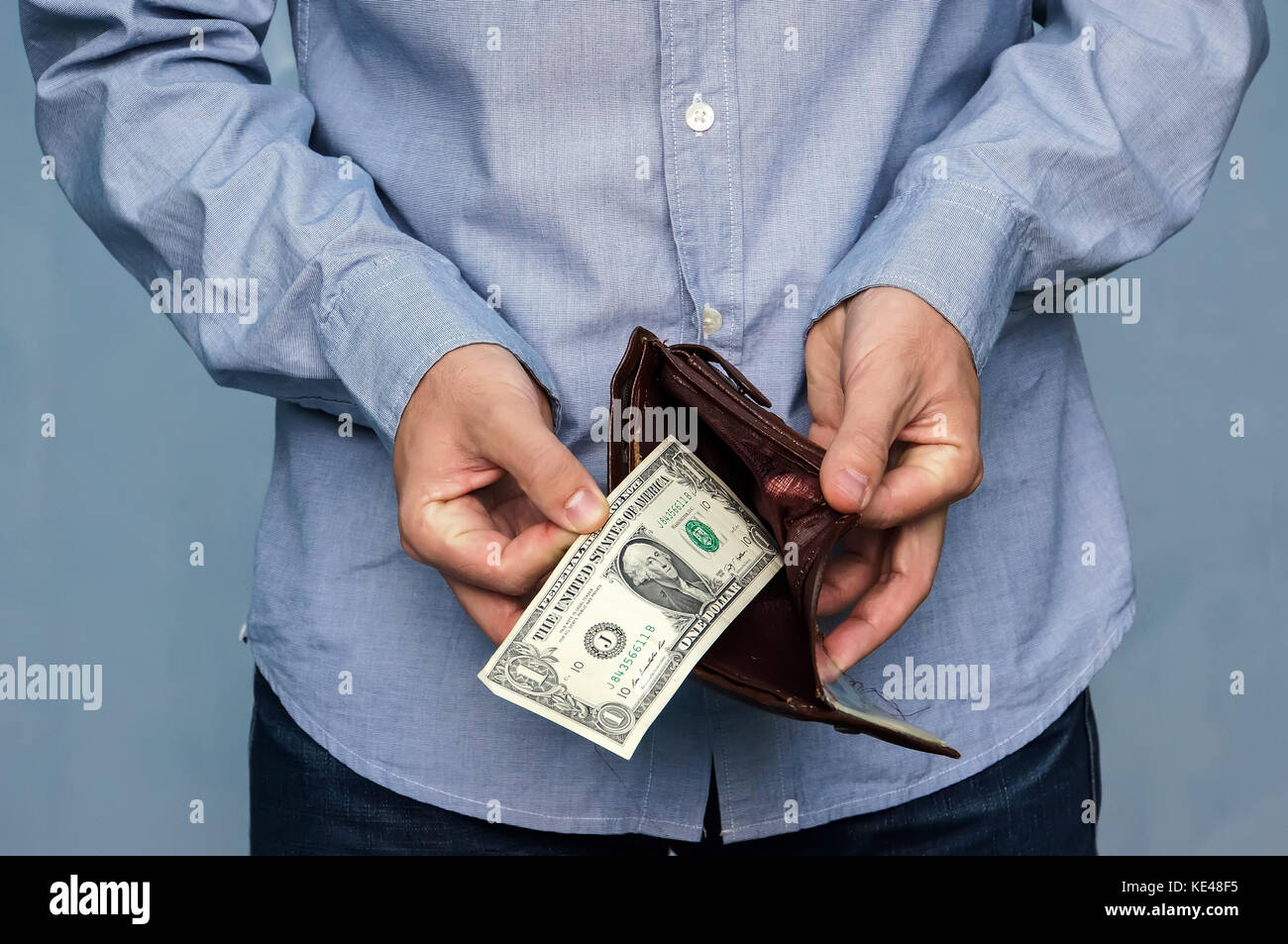 L'uomo ottiene denaro dal portafogli. mani close-up tenendo un dollaro e un portafoglio in pelle. la povertà e la disoccupazione. Foto Stock