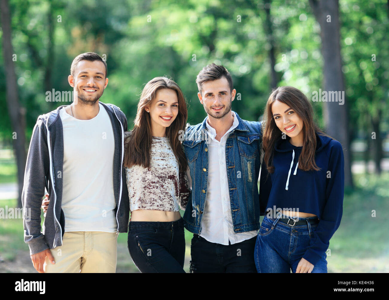 Quattro giovani allegro amici stanno camminando sulla giornata calda. caucasico due uomini e due donne per divertirsi insieme all'esterno. mezzo corpo ritratto di peopl sorridente Foto Stock