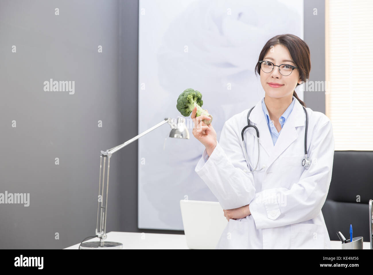 Smile medico donna con broccoli in posa Foto Stock