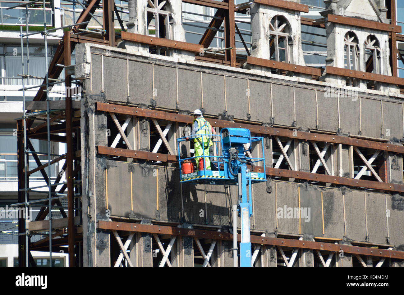 Workman ispezione rimasta solo la facciata di un parzialmente demolito palazzo. Foto Stock