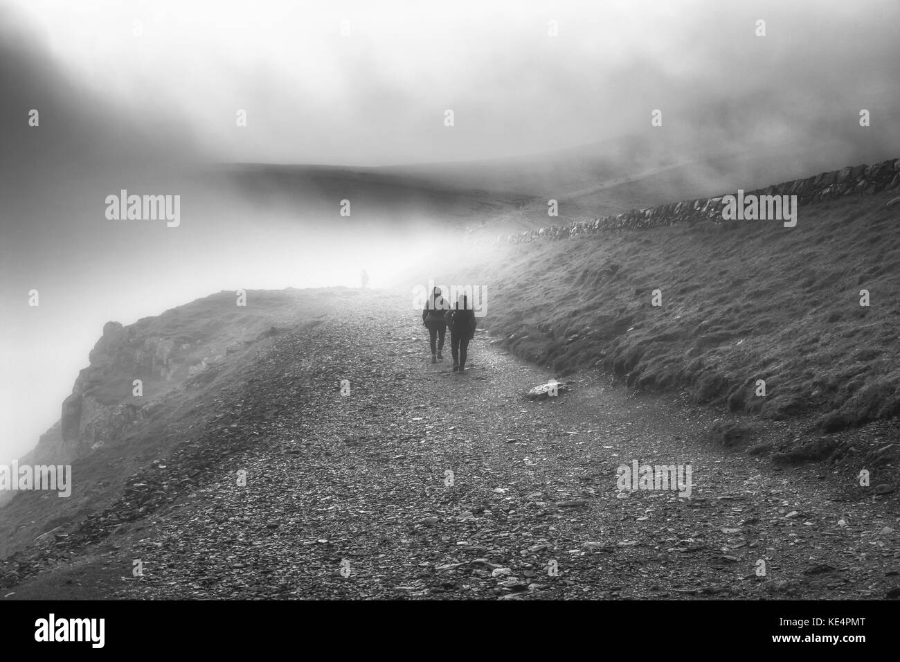 Persone che lottano per salire Mount Snowdon nella nebbia invernale, in bianco e nero Foto Stock