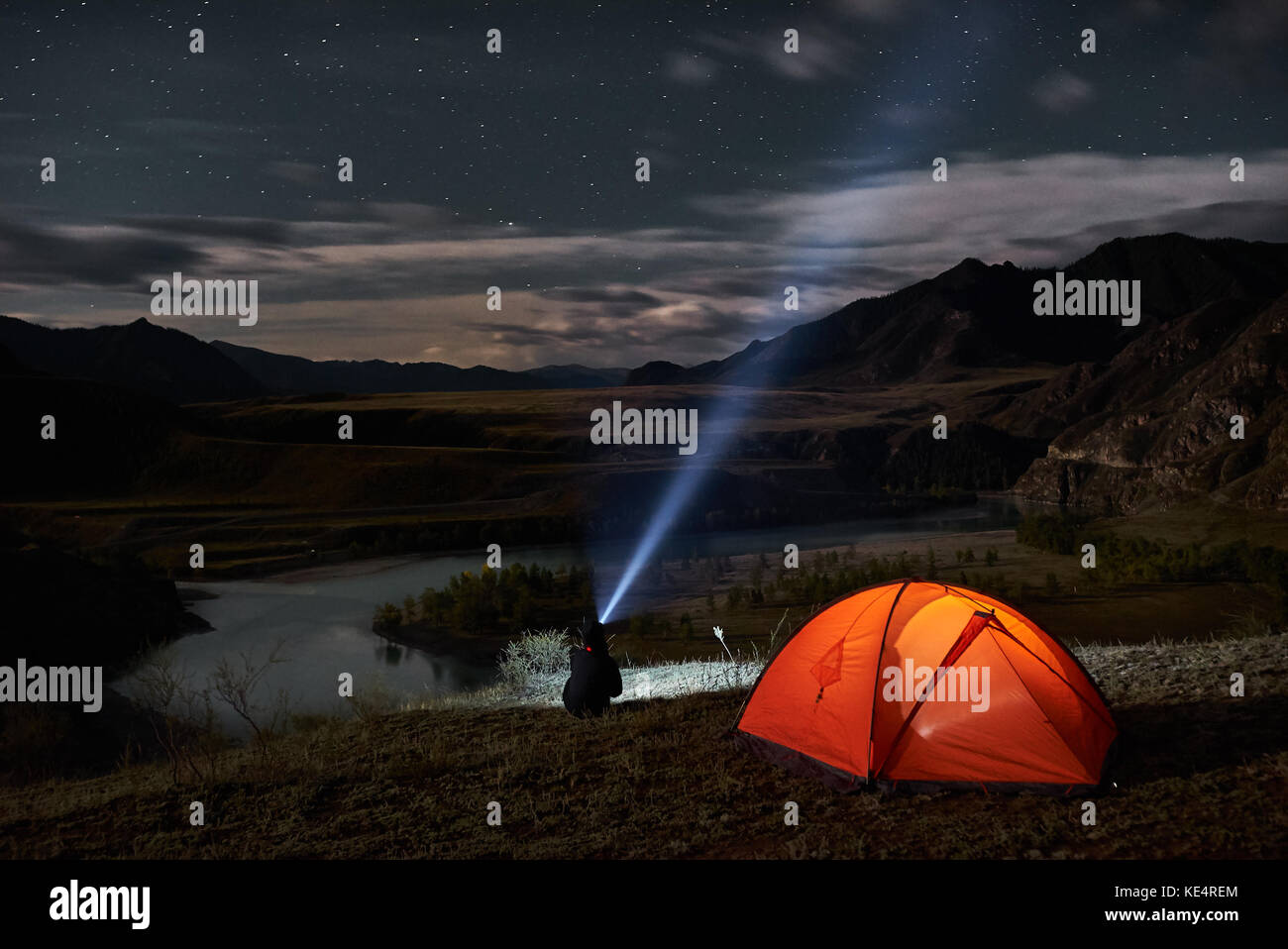 L'uomo turistico con torcia elettrica vicino al suo accampamento tenda a notte. Foto Stock