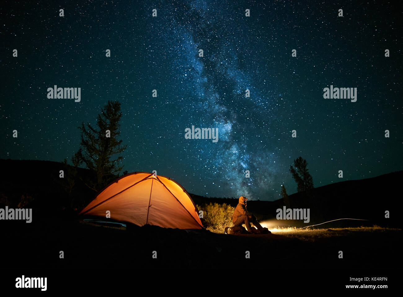 L'uomo tourist vicino al suo accampamento tenda a notte. Foto Stock