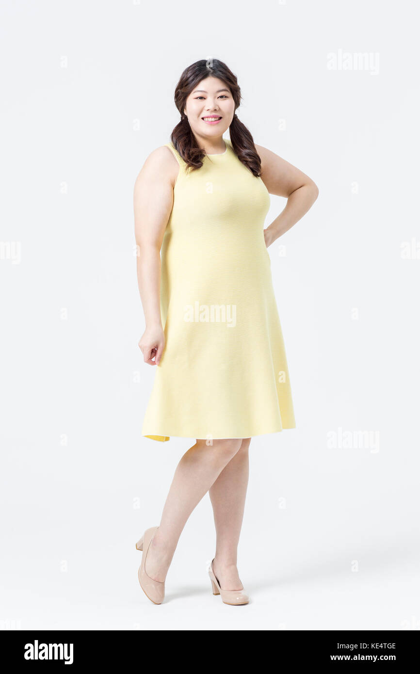 Sorridente giovane donna grassa in abito giallo in posa Foto Stock