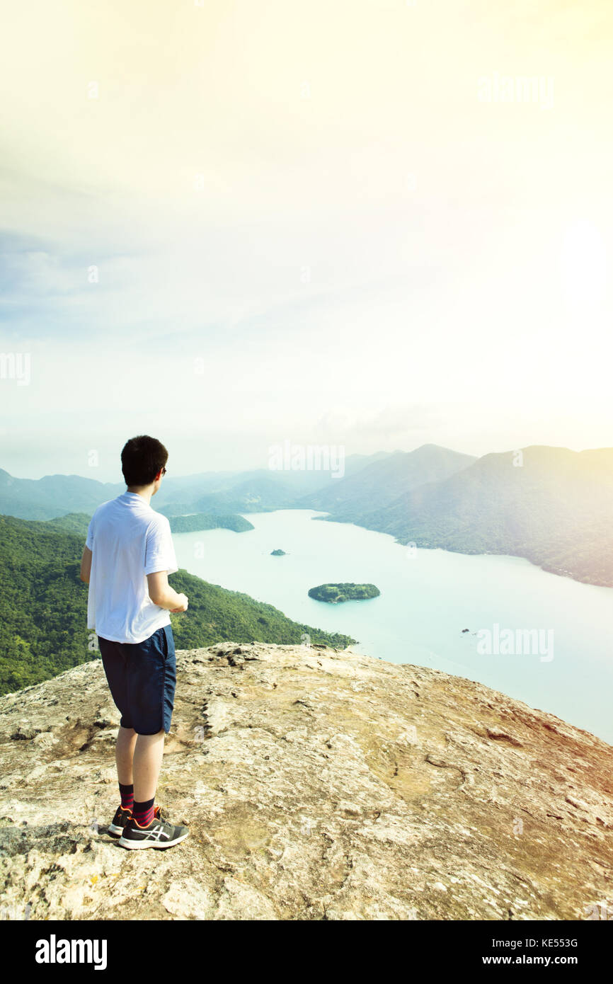 Giovane escursionista maschile che si affaccia sul Saco de Mamangua dal picco del Pan di zucchero sulla Costa Verde vicino Paraty, Brasile Foto Stock