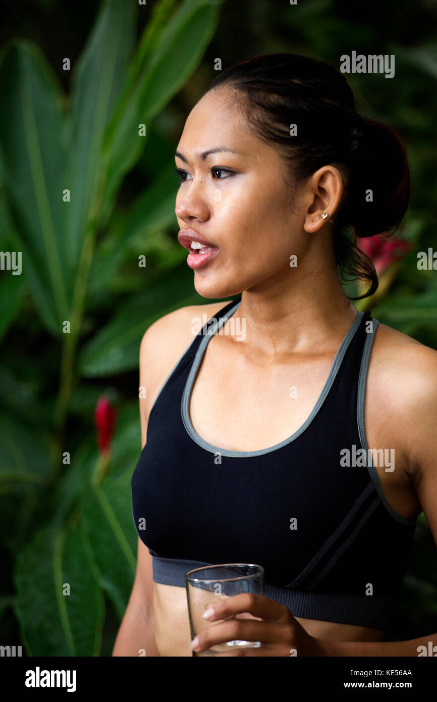 Donna asiatica in abiti di fitness con un bicchiere di acqua Foto Stock