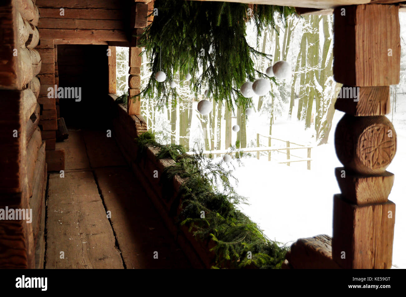 Il bianco e il verde holiday decoro ad un portico di un vecchio cottage di registro con rami di abete bianco e palle di Natale. Foto Stock