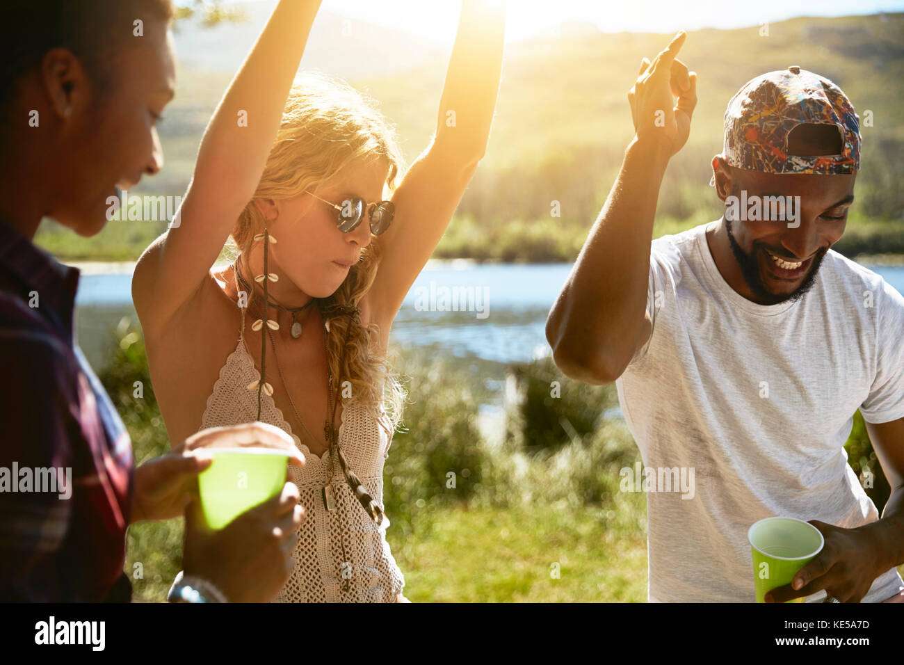 Divertenti giovani amici che ballano sul soleggiato lungofiume estivo Foto Stock