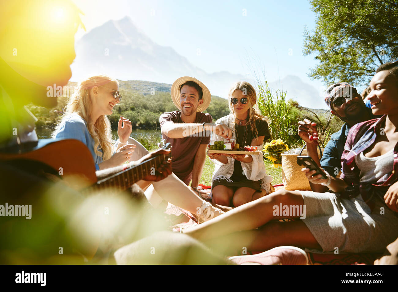 I giovani amici si divertono a fare un picnic nel soleggiato parco estivo Foto Stock