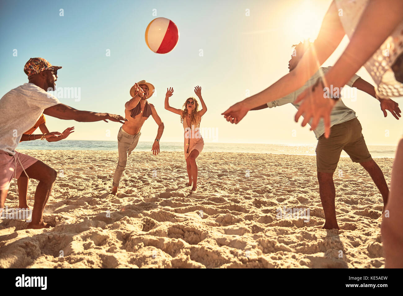 Giocosi giovani amici che giocano con la palla da spiaggia in estate soleggiata spiaggia Foto Stock