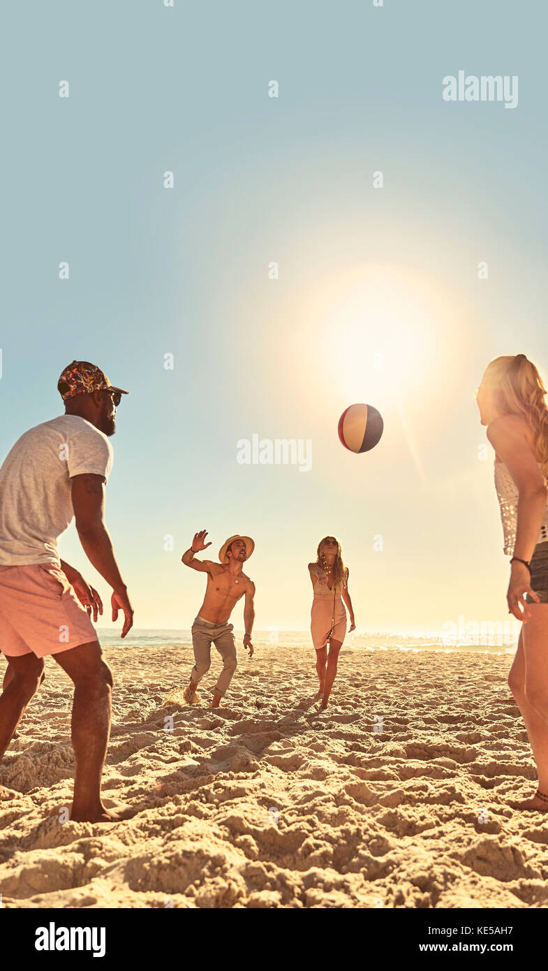 Giovani amici che giocano con la palla da spiaggia sulla soleggiata spiaggia estiva Foto Stock