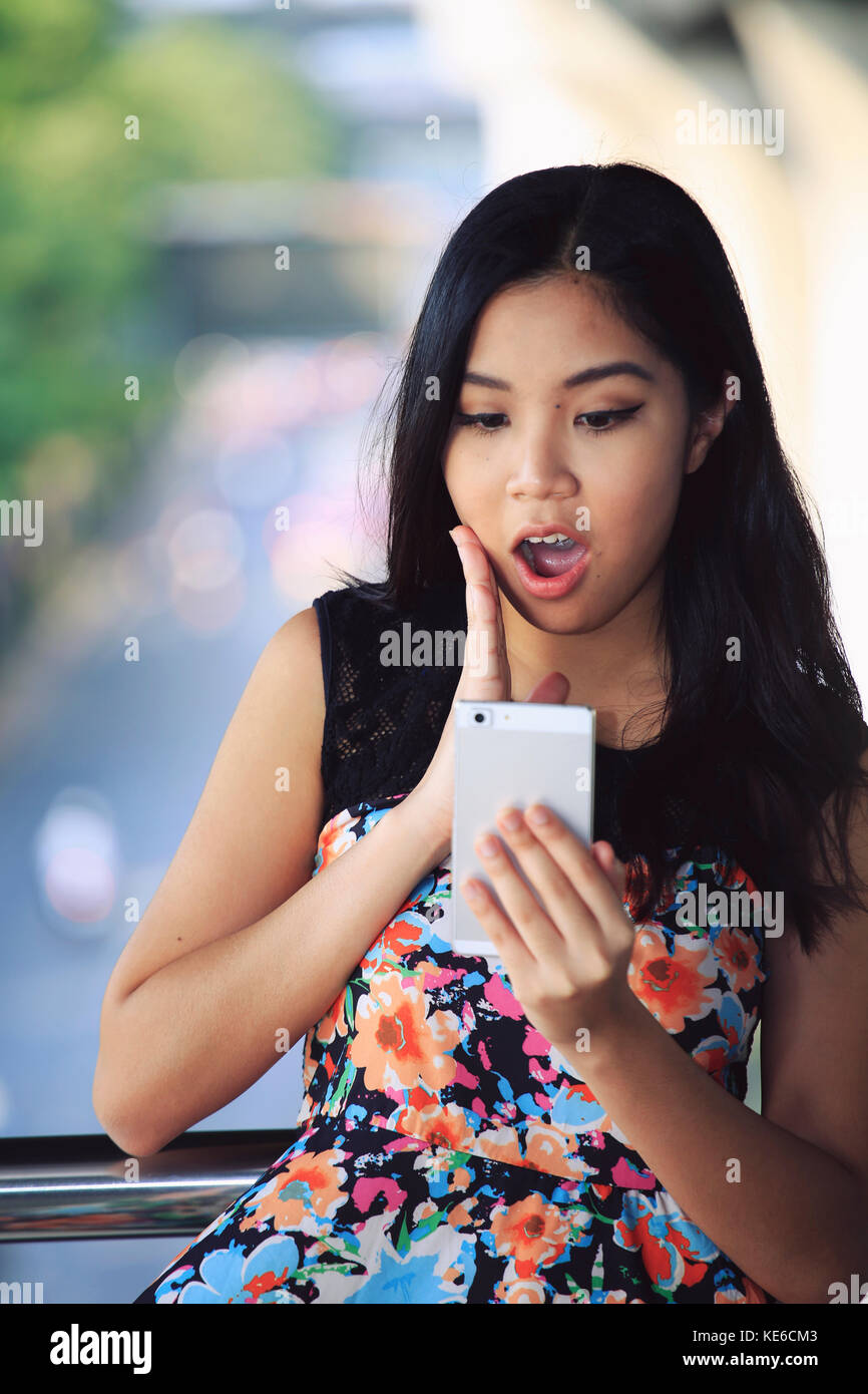 Giovane donna indignato per un messaggio di testo sul suo telefono cellulare Foto Stock