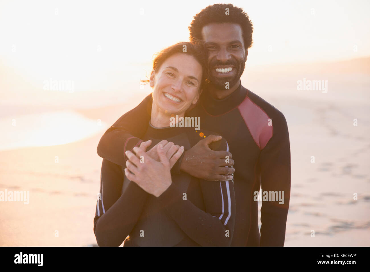Ritratto sorridente, affettuosa coppia abbracciando al tramonto spiaggia estiva Foto Stock