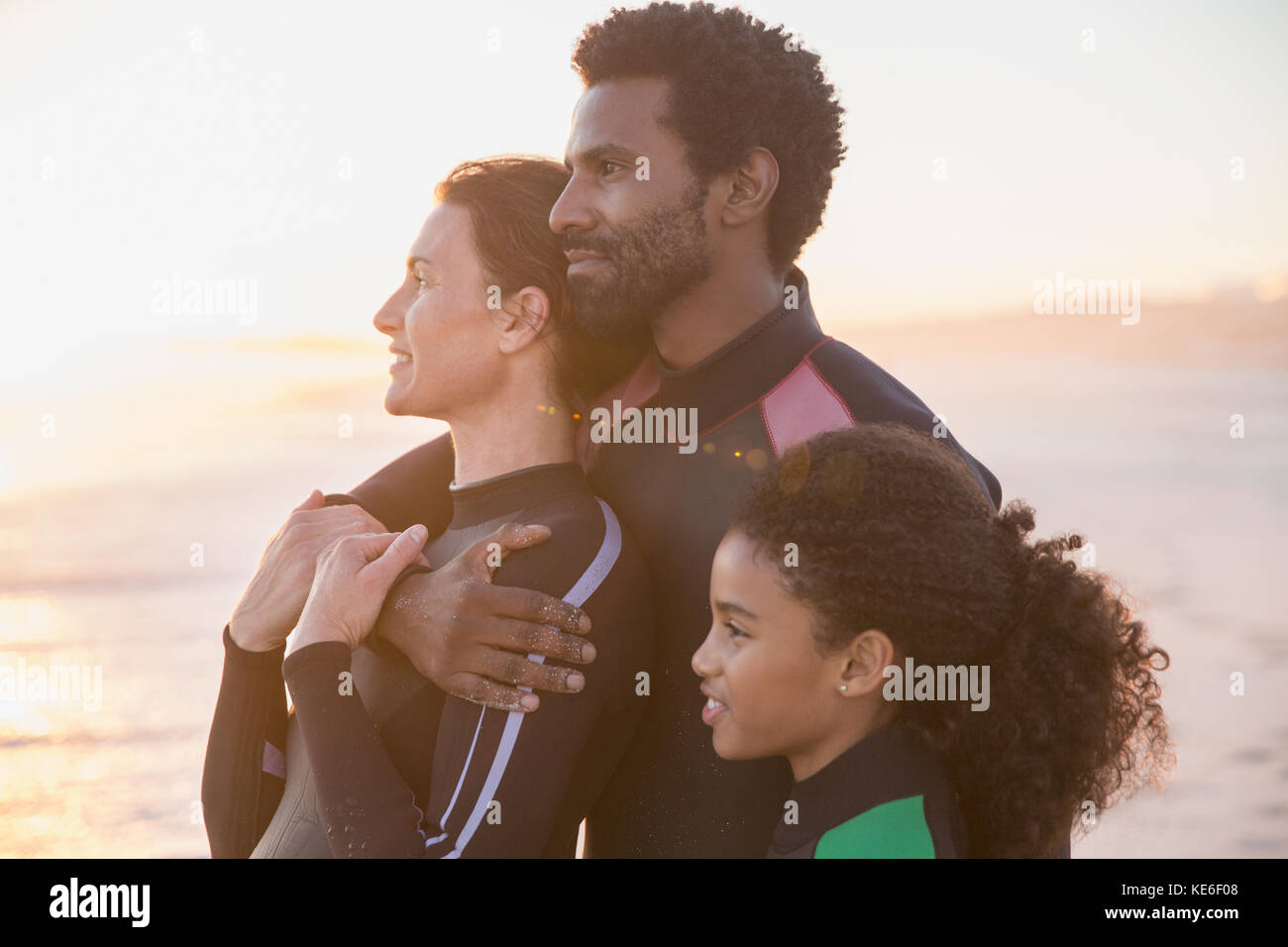 Serena e affettuosa famiglia che si affaccia sulla spiaggia estiva del tramonto Foto Stock