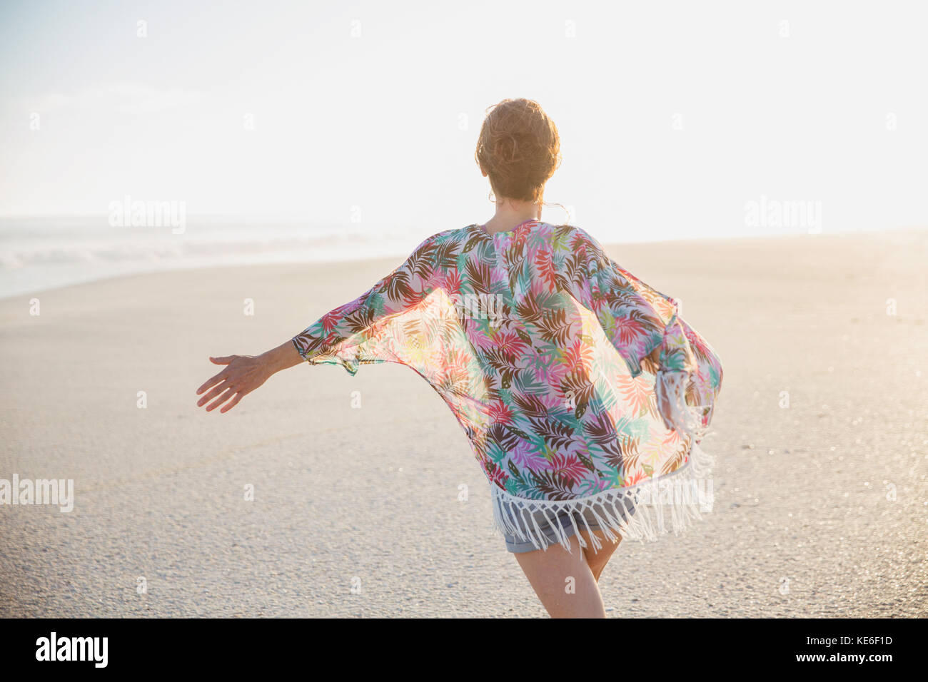 Donna spensierata che cammina con le braccia distese sulla spiaggia estiva Foto Stock