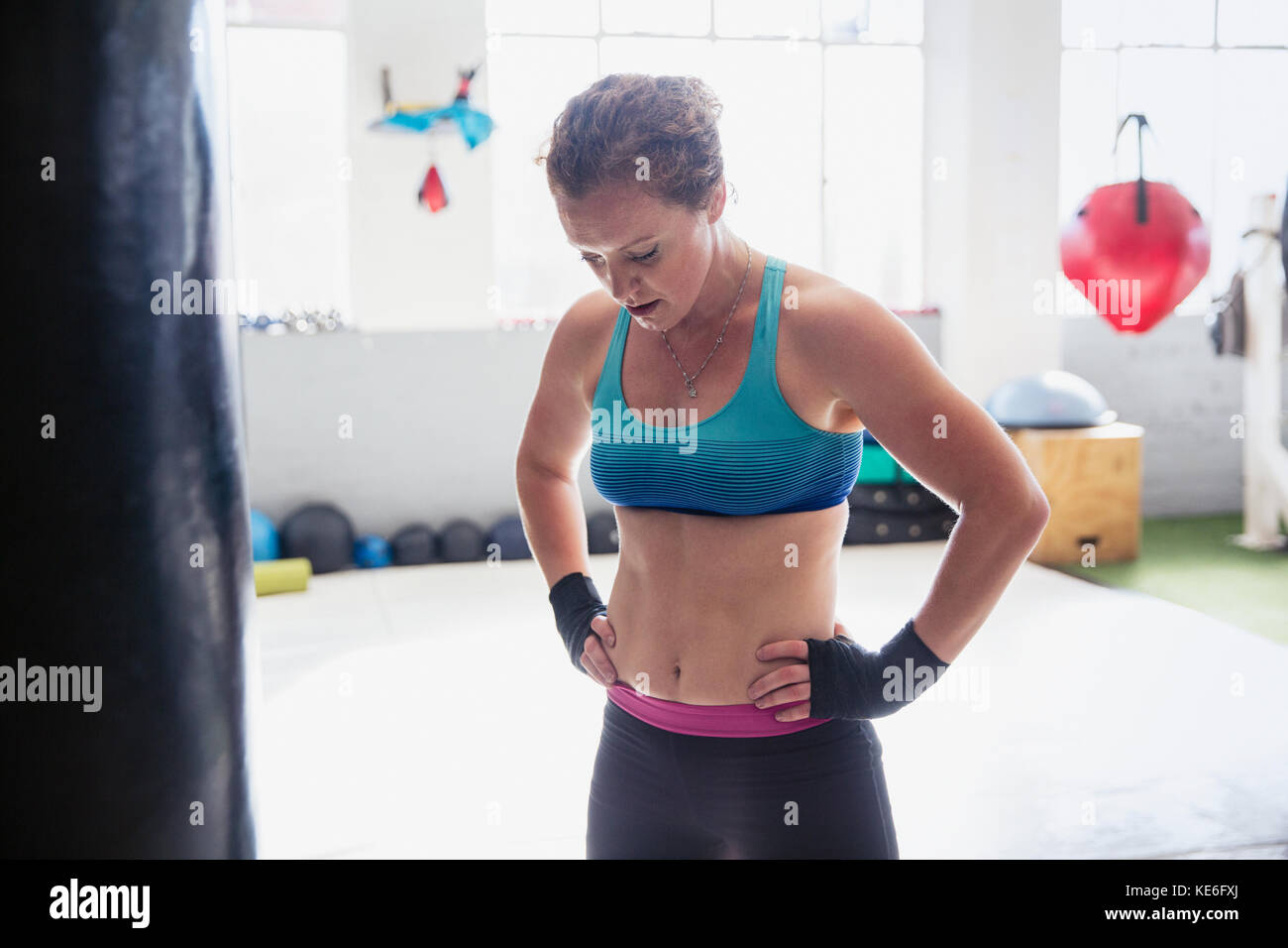 Pugile stanco che riposa con le mani sui fianchi in palestra Foto Stock