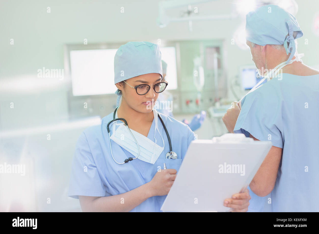 Donna chirurgo che esamina i documenti negli appunti in sala operatoria Foto Stock