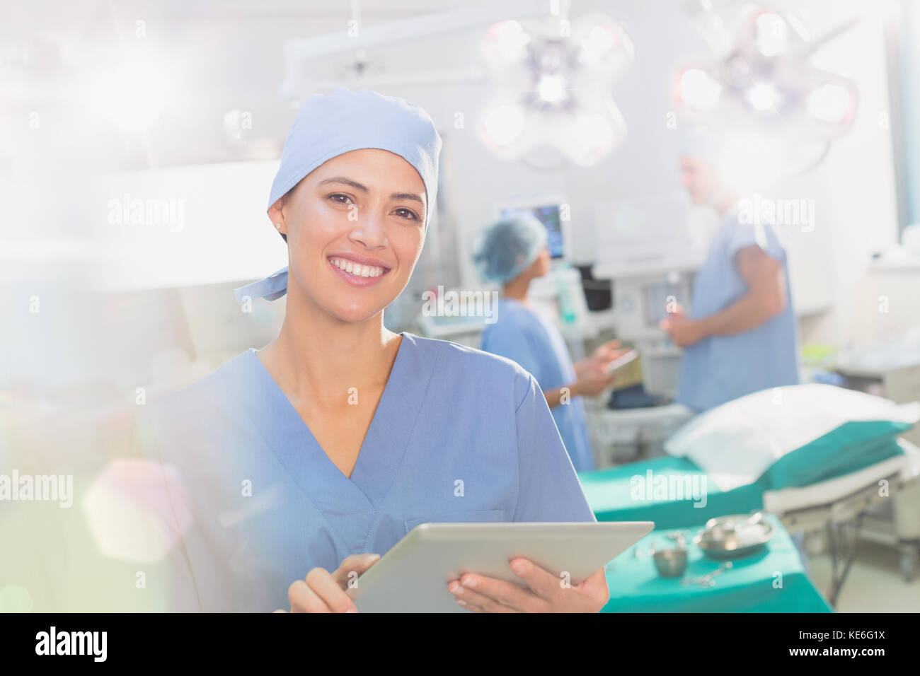 Ritratto sorridente e sicuro chirurgo utilizzando tablet digitale in sala operatoria Foto Stock