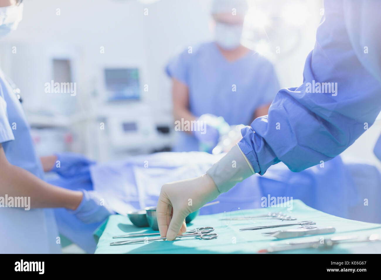 Il chirurgo in guanti di gomma raggiunge le forbici chirurgiche sul vassoio in sala operatoria Foto Stock