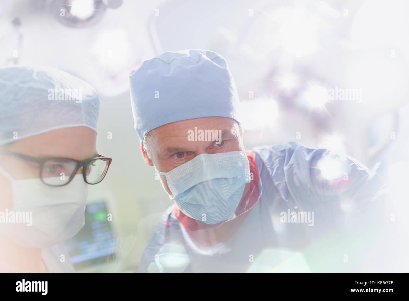 Chirurghi che indossano una maschera chirurgica che guarda in basso in sala operatoria Foto Stock
