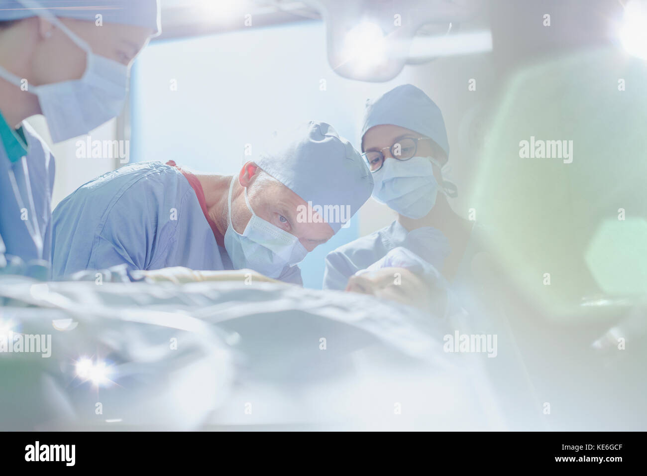 Chirurgo maschile focalizzato che esegue interventi chirurgici su pazienti di sesso femminile in attività camera Foto Stock