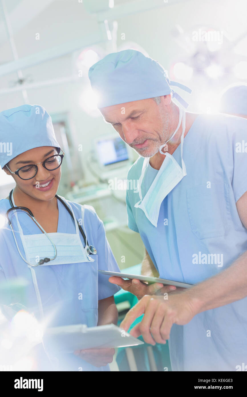 Chirurghi con tablet digitale e appunti che parlano in sala operatoria Foto Stock